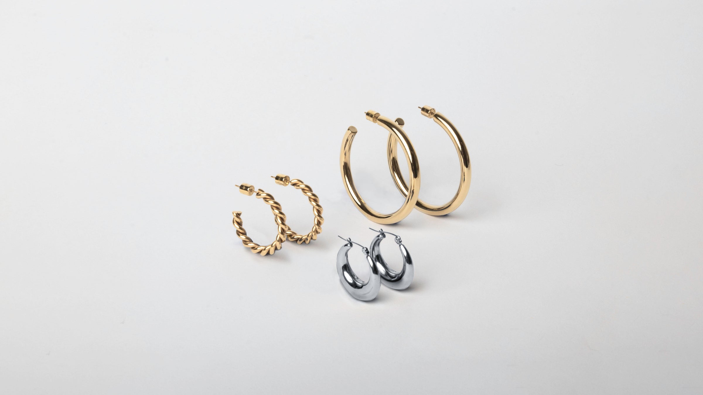 Three MARRIN COSTELLO hoops, showcasing the different styles and sizes of our earrings. Including the Michaela 2" Hoops and Rita Hoops, and Layla Hoops. All earrings are available in 14k gold plated stainless steel and polished stainless steel.