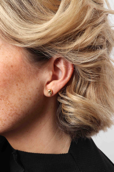 Marrin Costello wearing Marrin Costello Jewelry Hyde Studs skull post back earrings — for pierced ears. Waterproof, sustainable, hypoallergenic. 14k gold plated stainless steel.