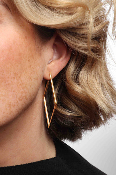 Marrin Costello wearing Marrin Costello Jewelry Maverick Hoops geometric diamond shaped post back earrings — for pierced ears. Waterproof, sustainable, hypoallergenic. 14k gold plated stainless steel.