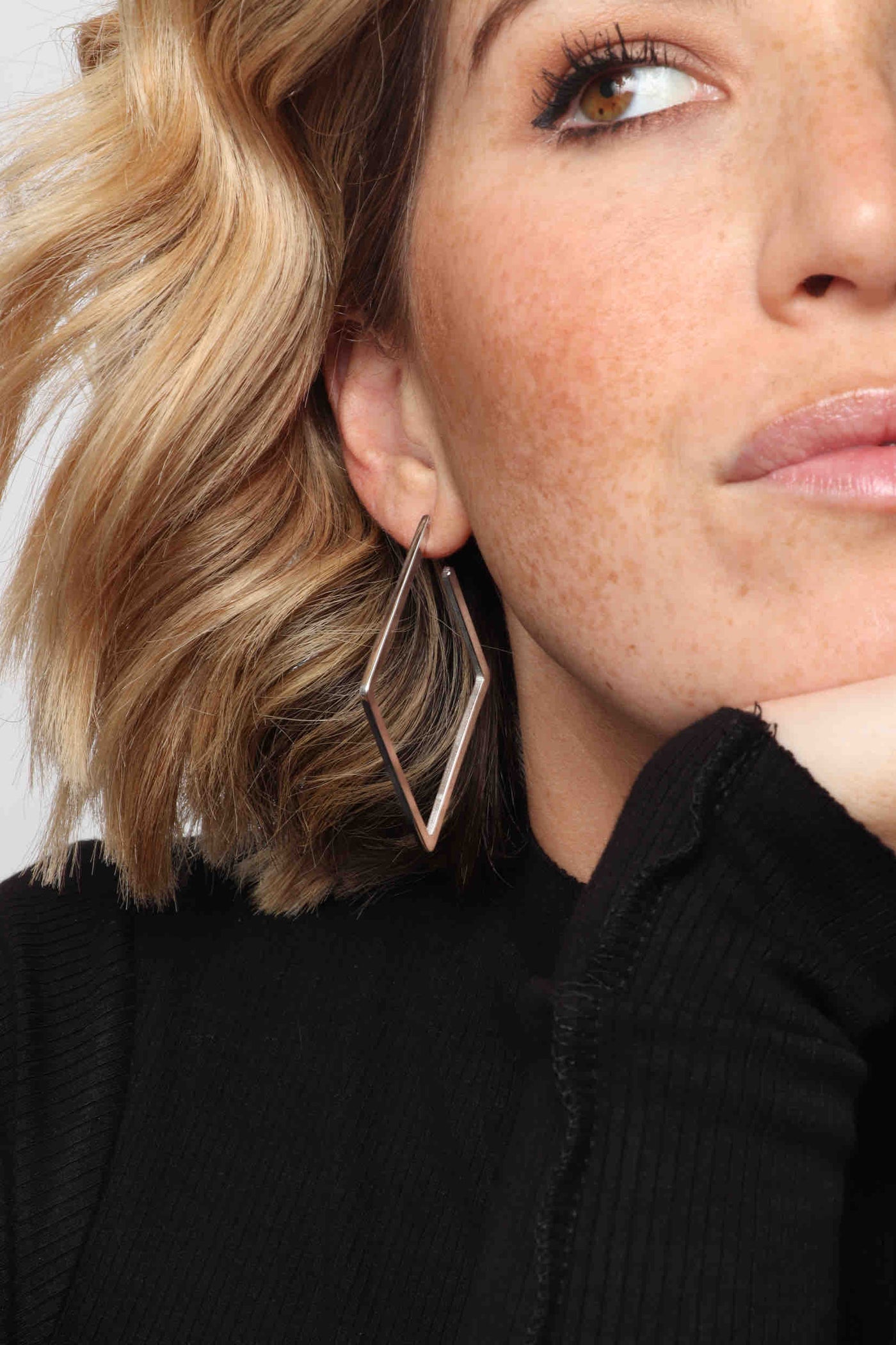 Marrin Costello wearing Marrin Costello Jewelry Maverick Hoops geometric diamond shaped post back earrings — for pierced ears. Waterproof, sustainable, hypoallergenic. Polished stainless steel.