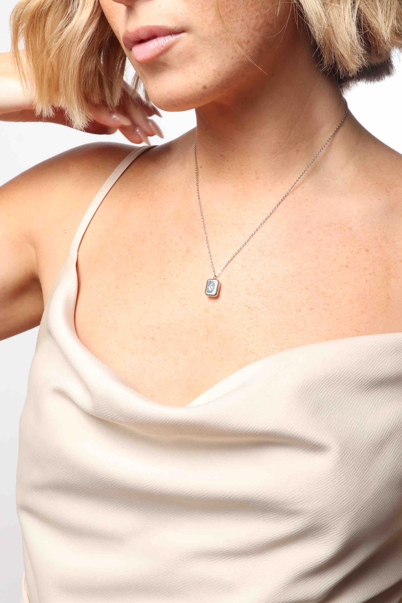 Marrin Costello wearing Marrin Costello Jewelry Orion Signet Pendant necklace with square pendant. Pendant is engraved with a star and CZ detail with spring ring clasp closure and extender. Waterproof, sustainable, hypoallergenic. Polished stainless steel.