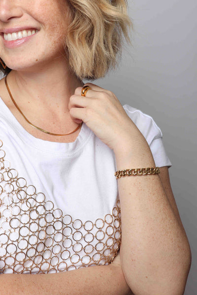 Mixing textures and patterns with this 14k gold plated stainless steel waterproof, non-tarnish, sustainable, hypoallergenic look by Marrin Costello Jewelry; diamond shaped Maverick Hoop earrings paired with our famous herringbone Ramsey Chain in 3mm width, along with our famous Cuban Link Queens Bracelet, dome Layla Ring, paired with a plain white t-shirt and gold mesh metallic vintage top