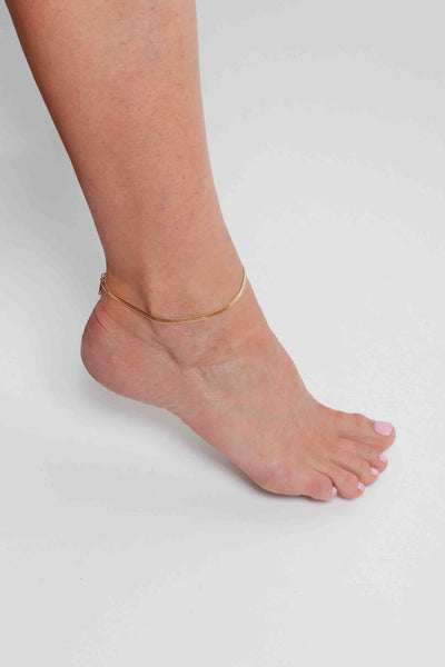 Marrin Costello wearing Marrin Costello Jewelry 3mm herringbone snake chain anklet with lobster clasp closure. Waterproof, sustainable, hypoallergenic. 14k gold plated stainless steel.