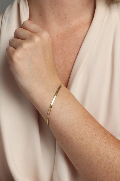 Marrin Costello wearing Marrin Costello Jewelry 3mm thick herringbone snake chain bracelet with lobster clasp closure. Waterproof, sustainable, hypoallergenic. 14k gold plated stainless steel.